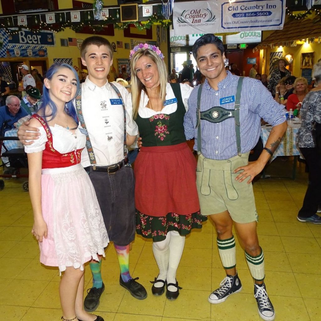 A group of four people, two men and two women, dressed in traditional German attire, are posing for a photo at the Big Bear Oktoberfest.