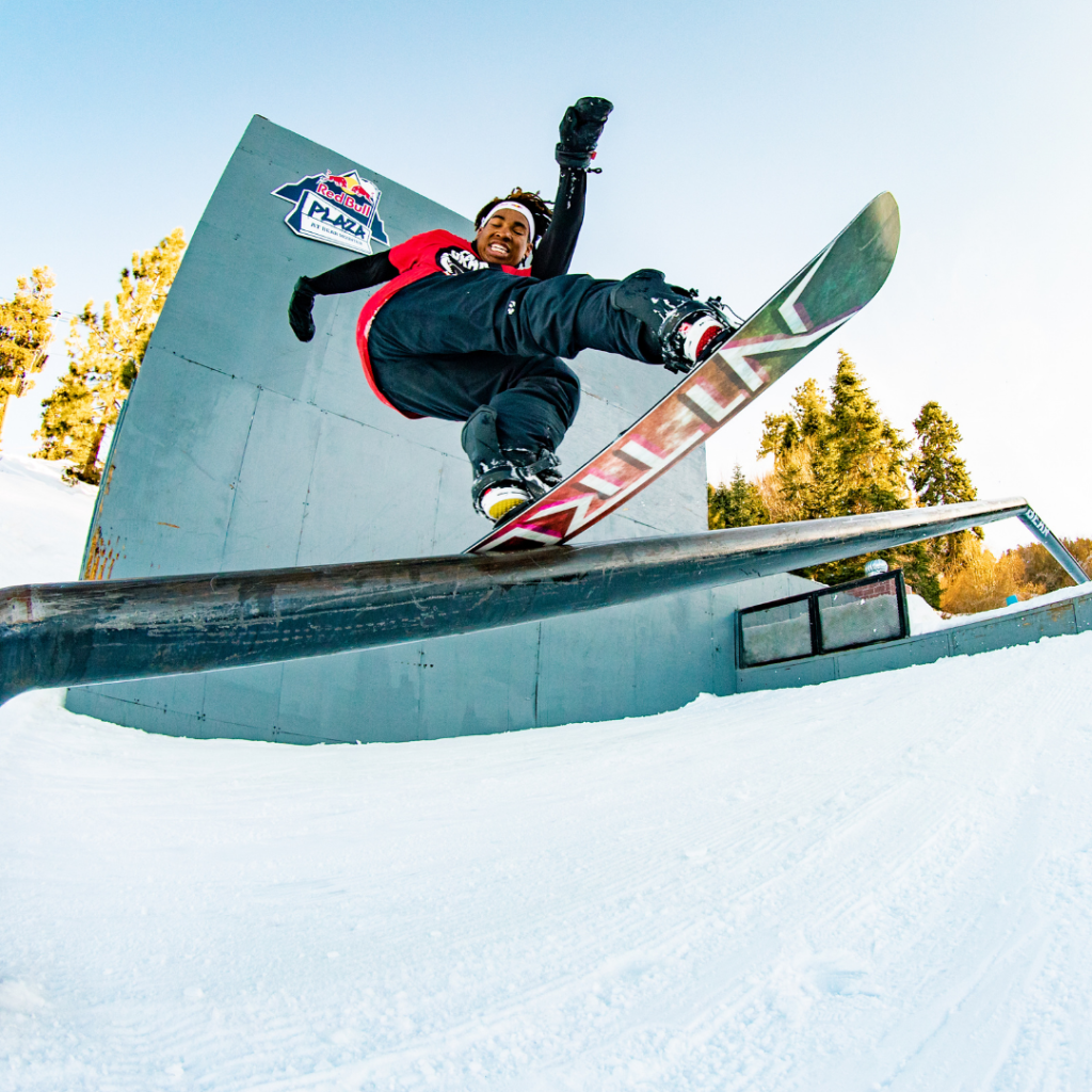 Snowboarder doing a jump trick on a rail at Big Bear snow park.