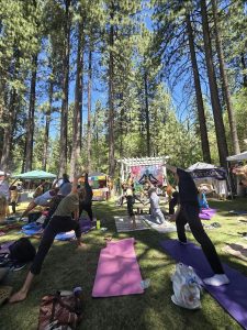 Community yoga class held outdoors at a wellness festival with people practicing surrounded by nature