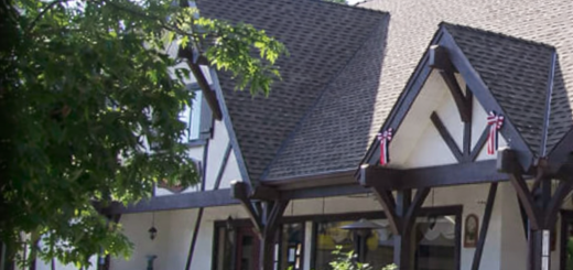 Exterior of Peppercorn Grill featuring a Tudor-style building with timber beams, stone planters, and trees in Big Bear Lake.