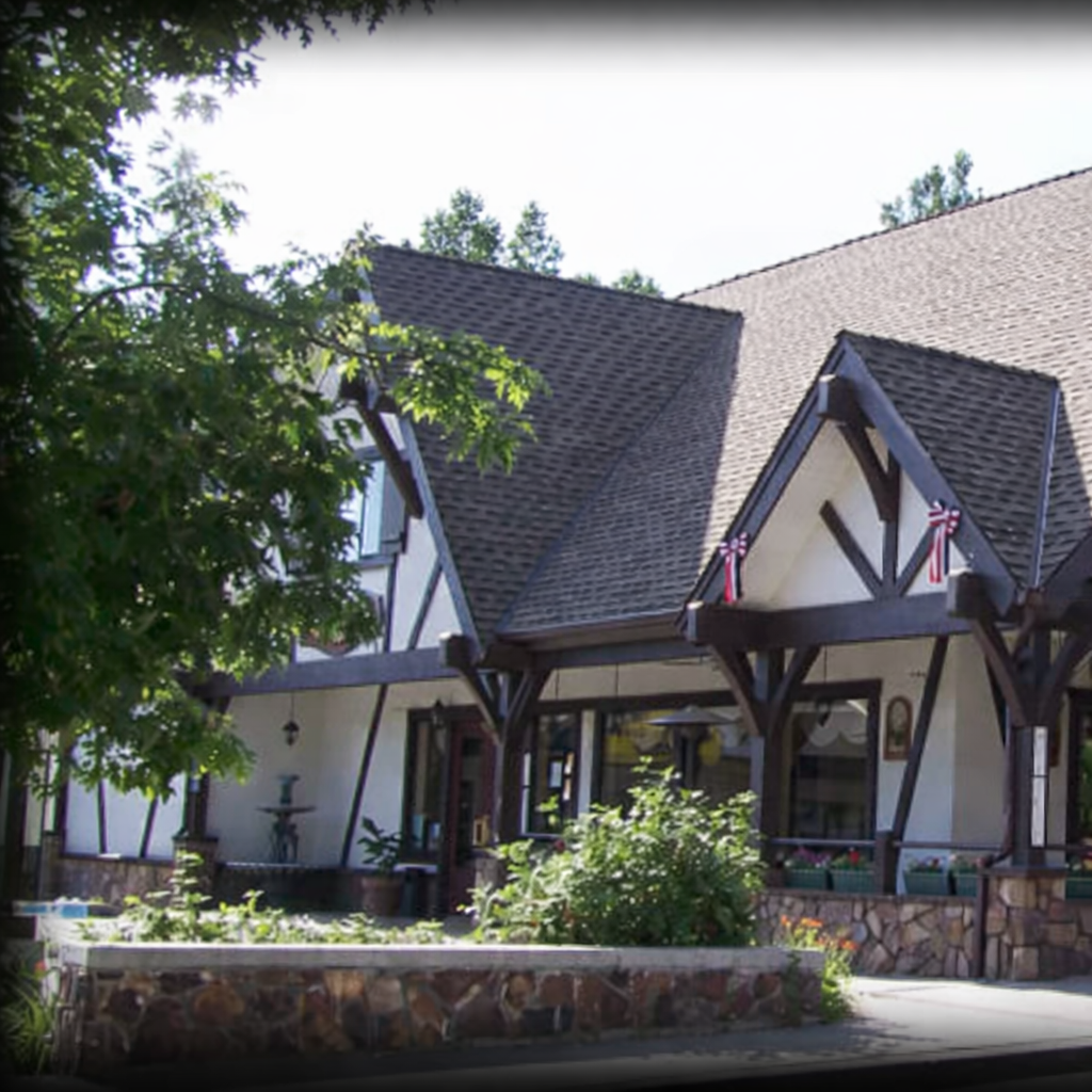 Exterior of Peppercorn Grill featuring a Tudor-style building with timber beams, stone planters, and trees in Big Bear Lake.