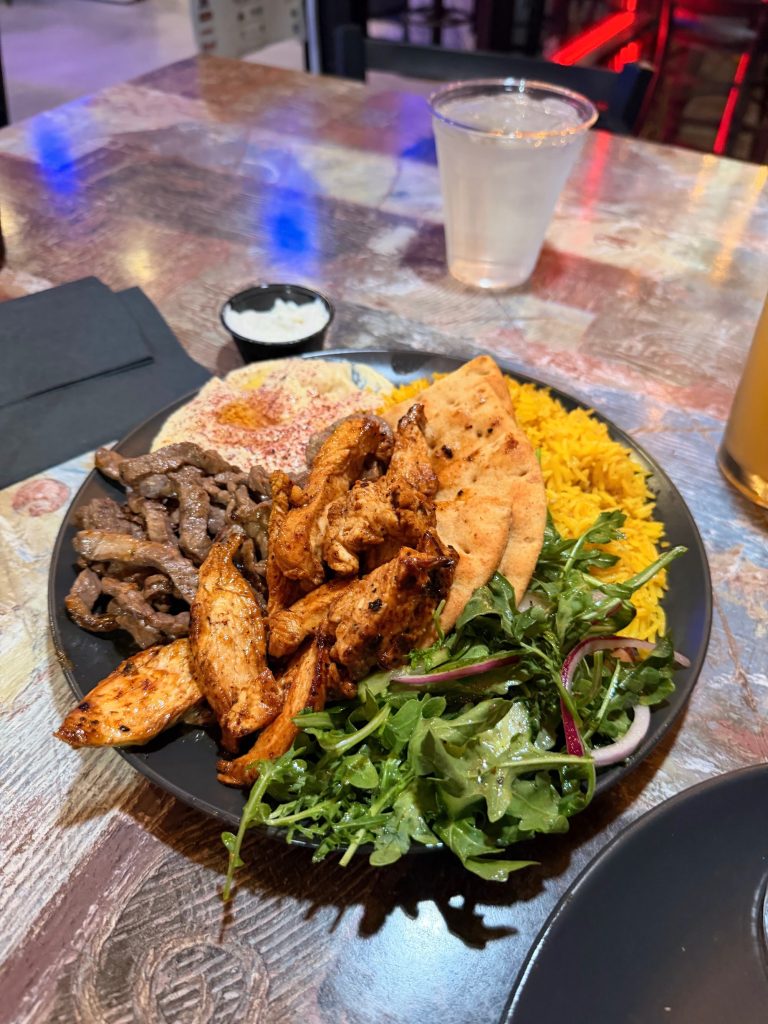Grilled chicken and beef platter served with rice, pita bread, hummus, and fresh salad at The Pita House.