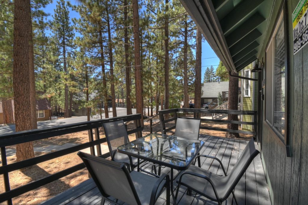 Private cabin deck with outdoor dining table and chairs surrounded by tall pine trees