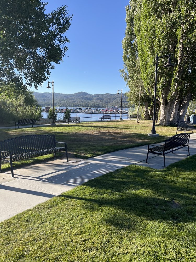 Scenic view of Rotary Pine Knot Park in Big Bear Lake with green grass, benches, and lake in the background