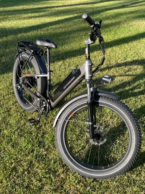 Black electric bike displayed on green grass during an outdoor ride setting