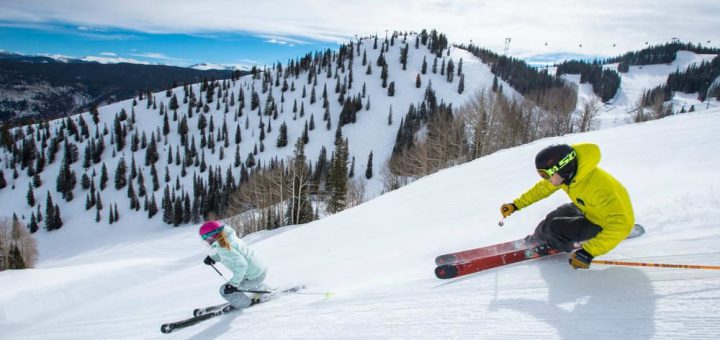 Two people skiing down a ski hill in winter in the mountains