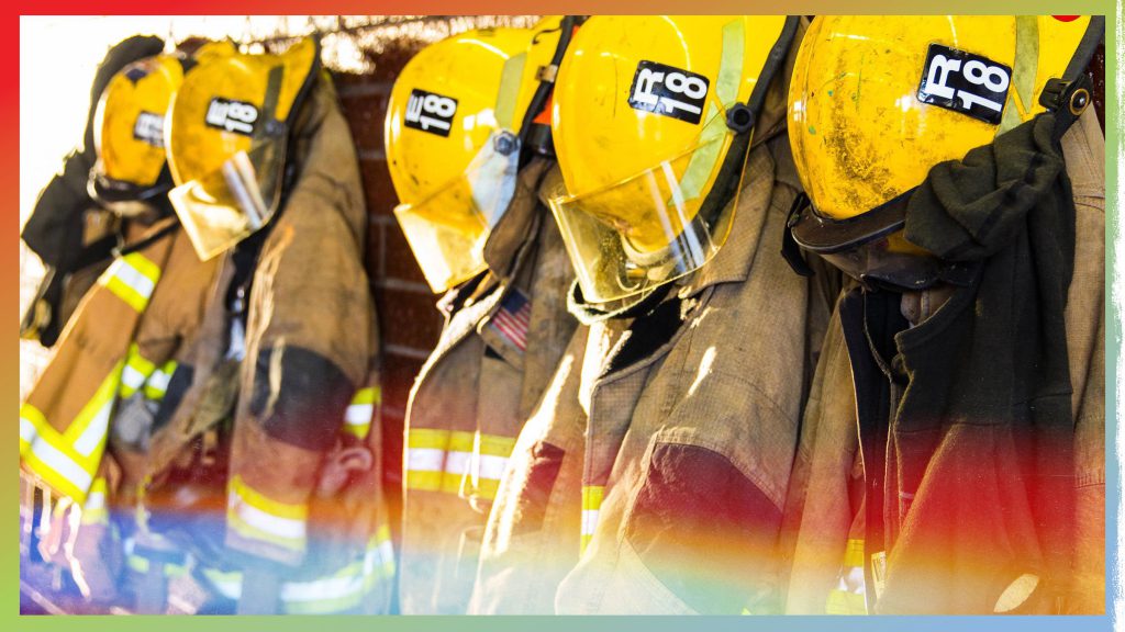 A row of five firefighter uniforms, featuring tan jackets and yellow helmets with the number 18, ready for use at a location such as Big Bear.
