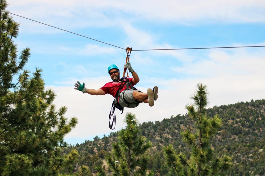 Person enjoying a thrilling zipline ride above the forest landscape in Big Bear.