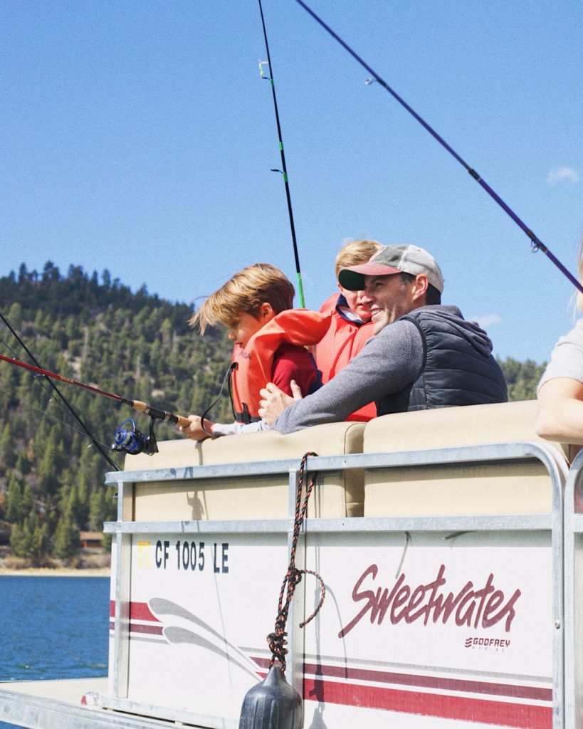 Family enjoying a fishing trip on Big Bear Lake from a boat surrounded by mountain views.