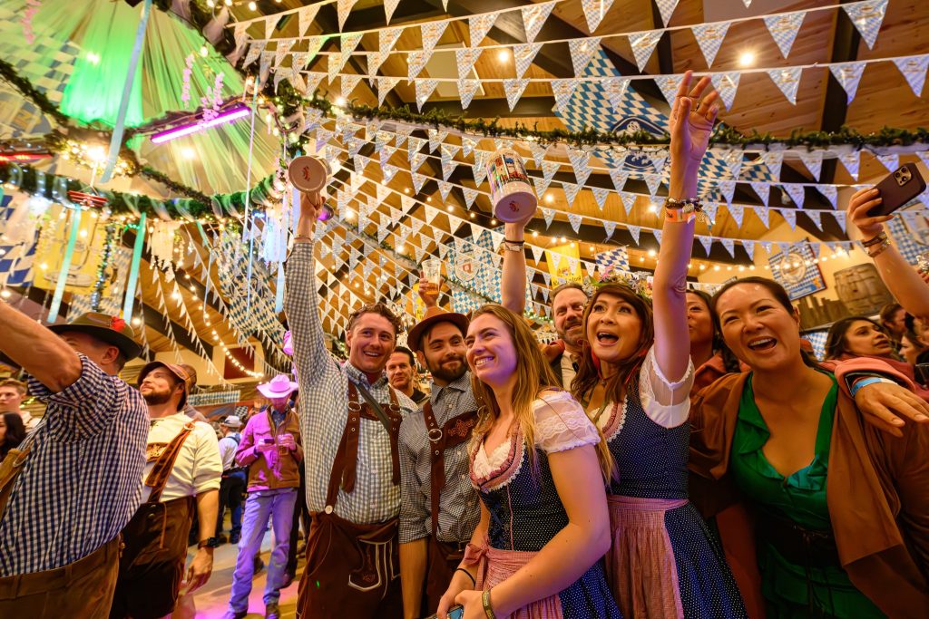 Guests celebrating Oktoberfest with festive decorations, traditional outfits, drinks, and live entertainment at Big Bear Lake