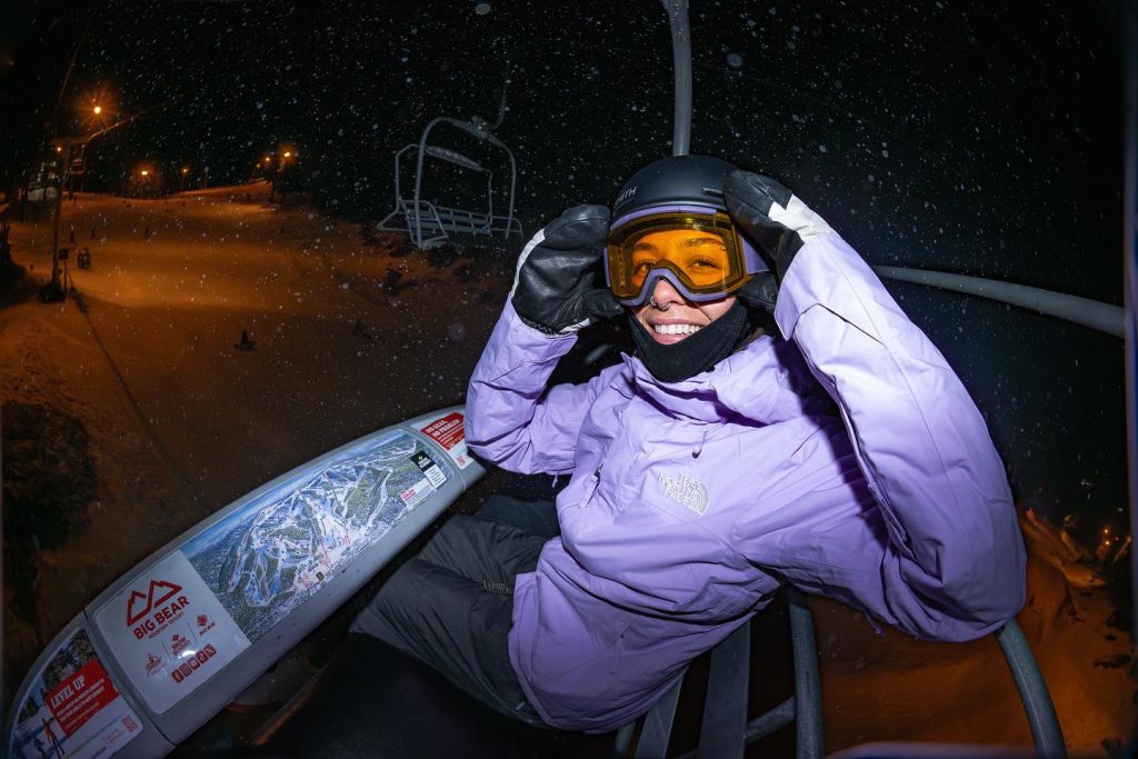 Skier enjoying a nighttime chairlift ride at Big Bear Mountain during snowfall
