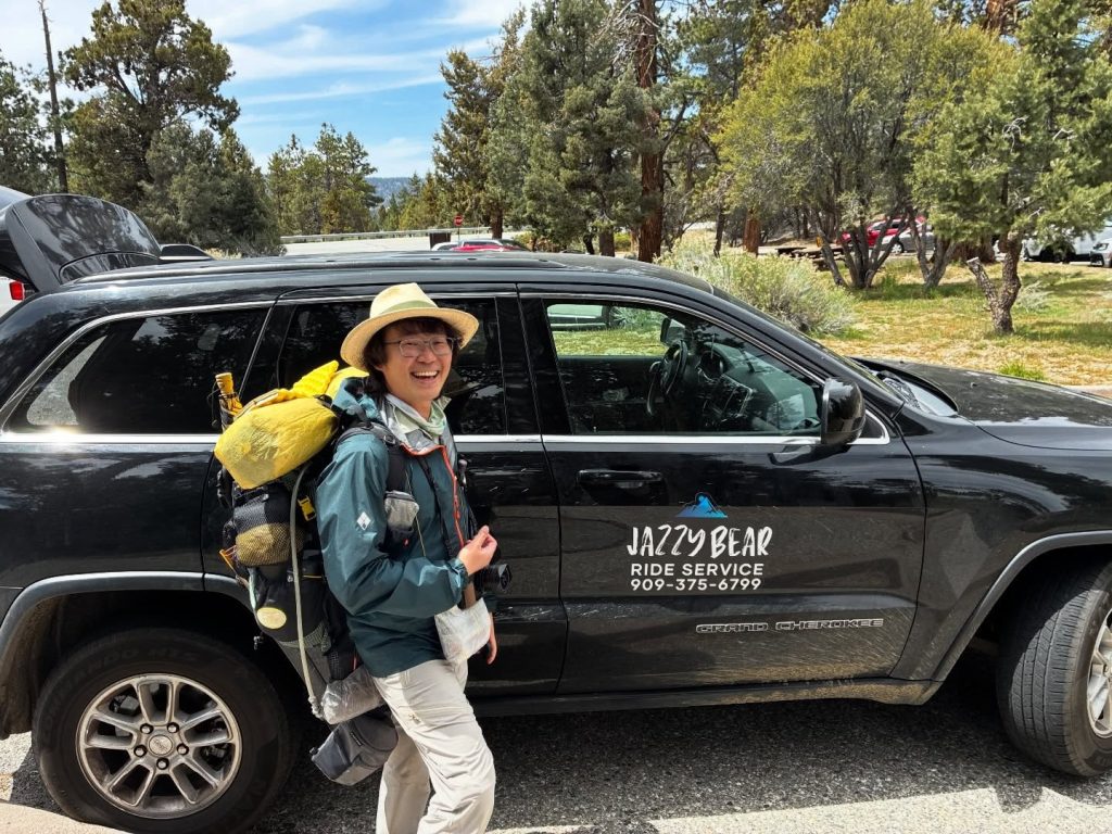 Jazzy Bear Ride Service vehicle providing transportation in Big Bear with passenger near a forest area