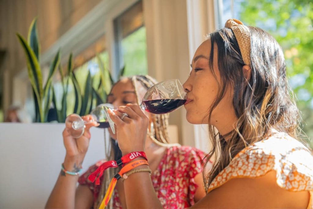Two guests enjoying a wine tasting experience indoors with glasses of red wine