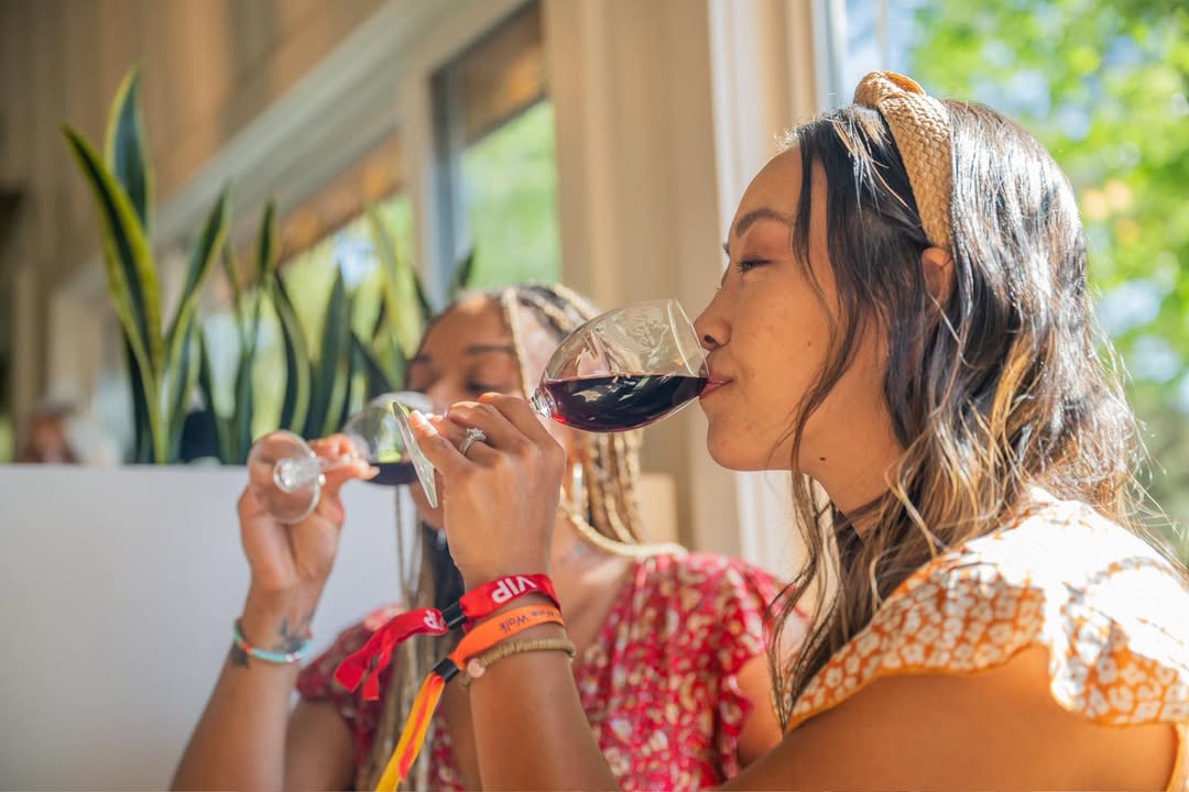 Two guests enjoying a wine tasting experience indoors with glasses of red wine