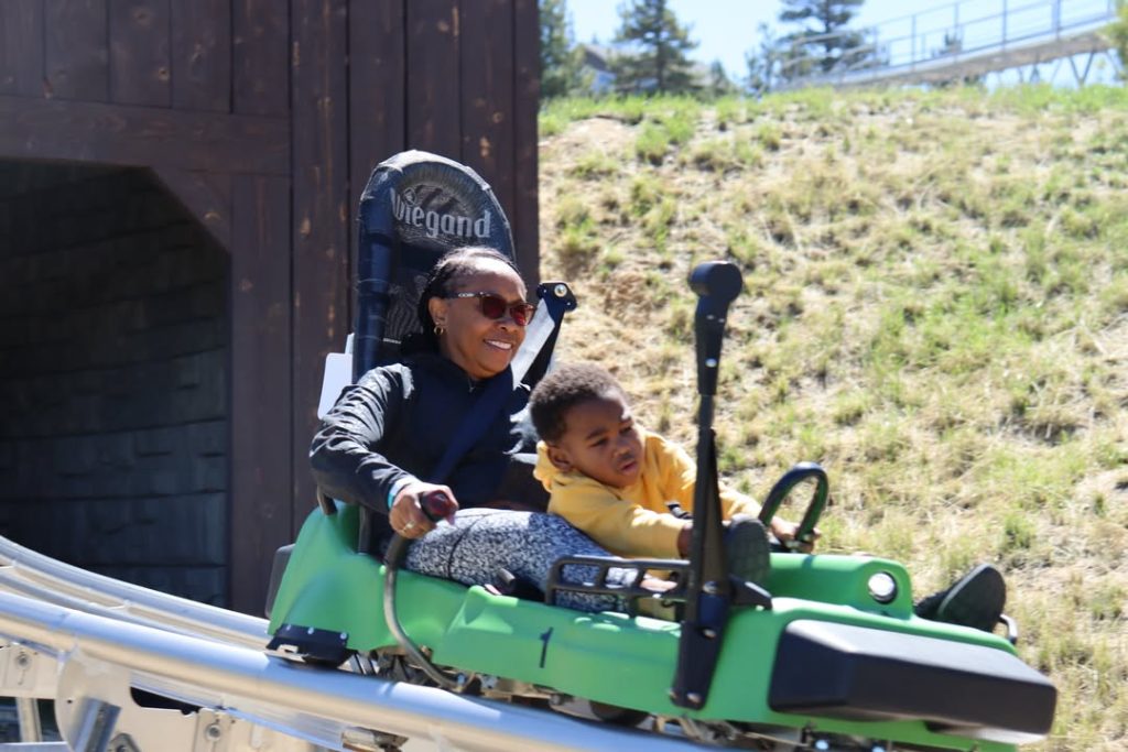 Adult and child riding an alpine slide attraction on a mountain track in Big Bear Lake