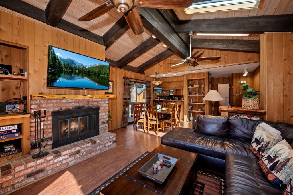 Cozy Snow Summit cabin living room with fireplace, dining area, and mountain-inspired interior