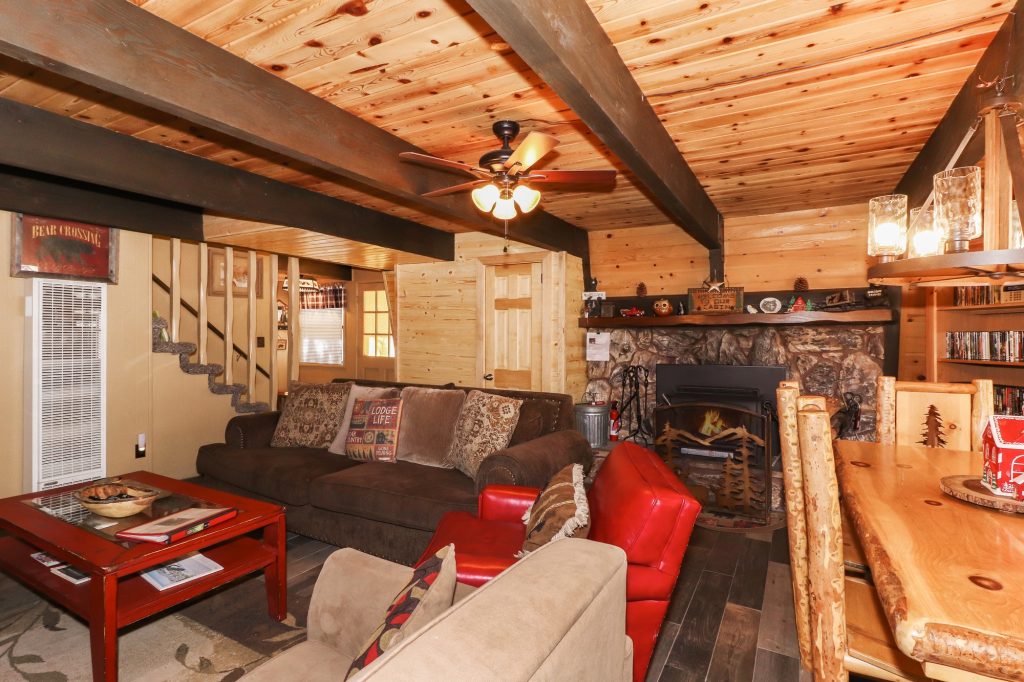 Cozy living room with wood beam ceiling, stone fireplace, and lodge-style furnishings