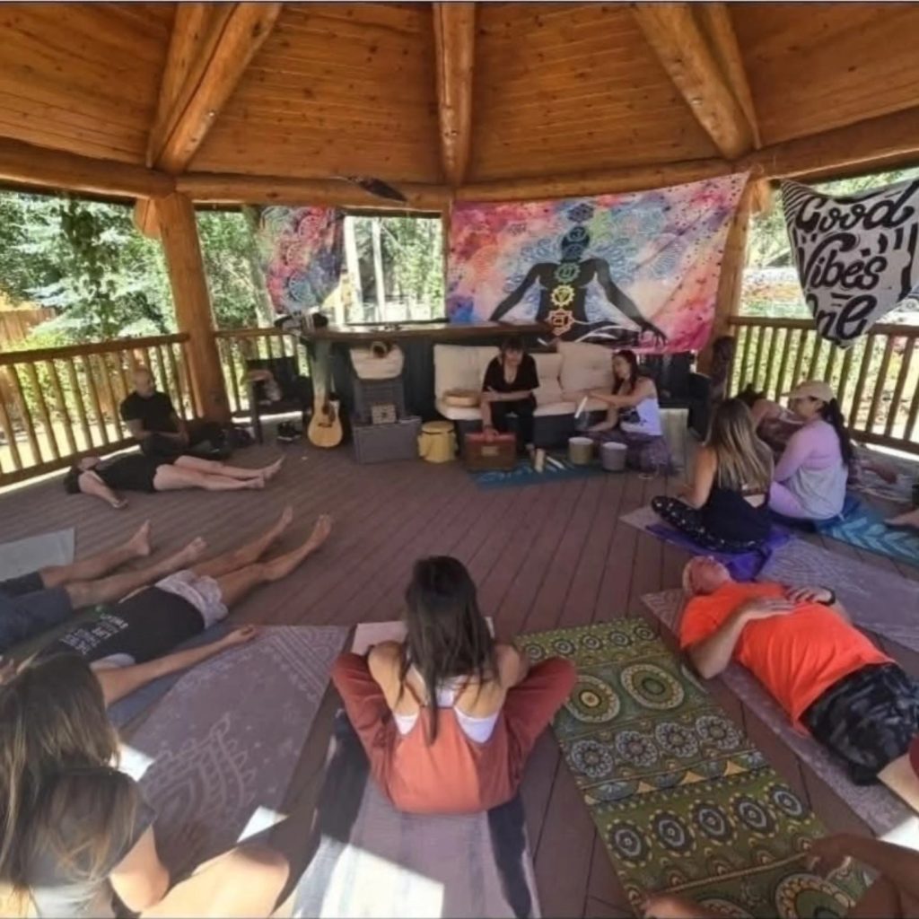 Group wellness session inside a wooden gazebo with participants relaxing during a sound healing activity