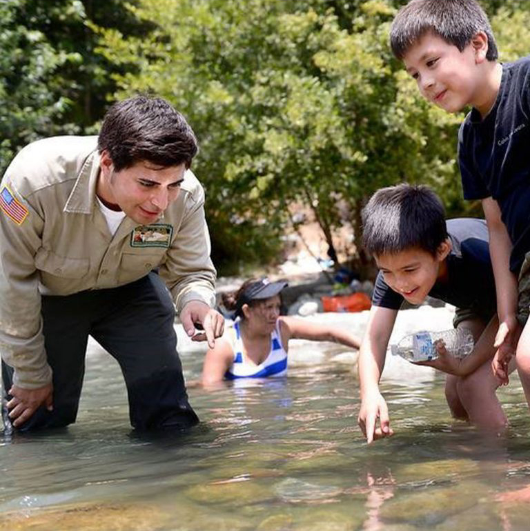 Children exploring a shallow stream with an instructor learning about nature and water outdoors