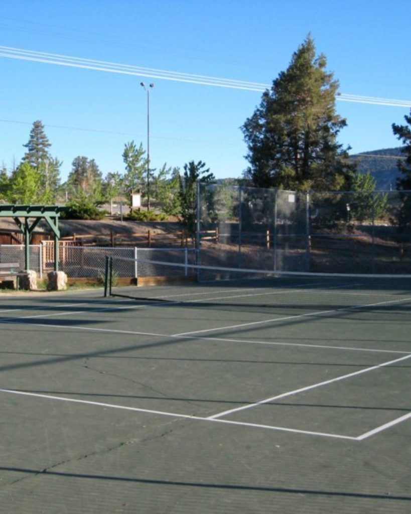 Tennis courts at Sugarloaf Park in Big Bear surrounded by pine trees, open space, and scenic mountain views.