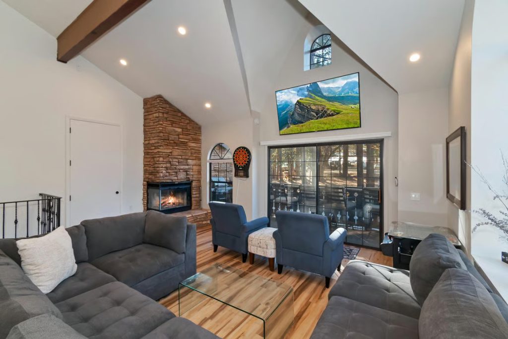 Cozy Big Bear cabin living room with comfortable sofas, a stone fireplace, wood flooring, and mountain-inspired decor