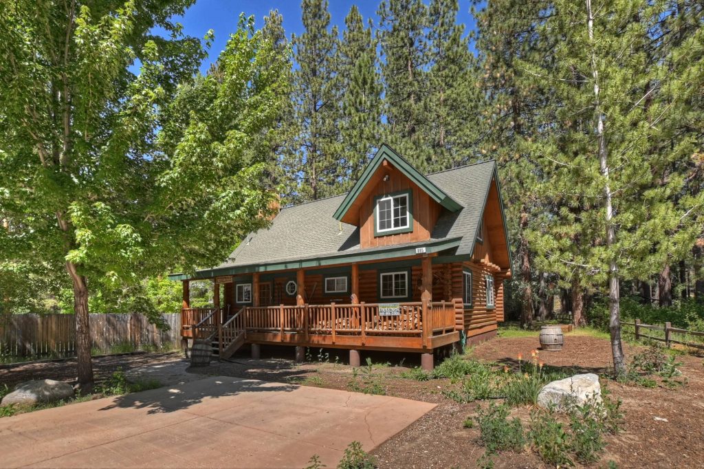 Beautiful log cabin exterior surrounded by pine trees with wooden porch and forest mountain setting in a peaceful retreat area