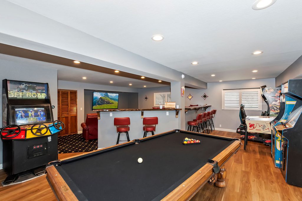 A Big Bear game room featuring a billiards table, arcade machines, and a bar area with red stools.