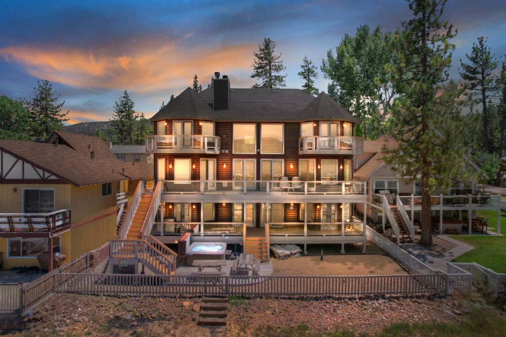 Lakefront home with multiple balconies and outdoor living spaces at sunset