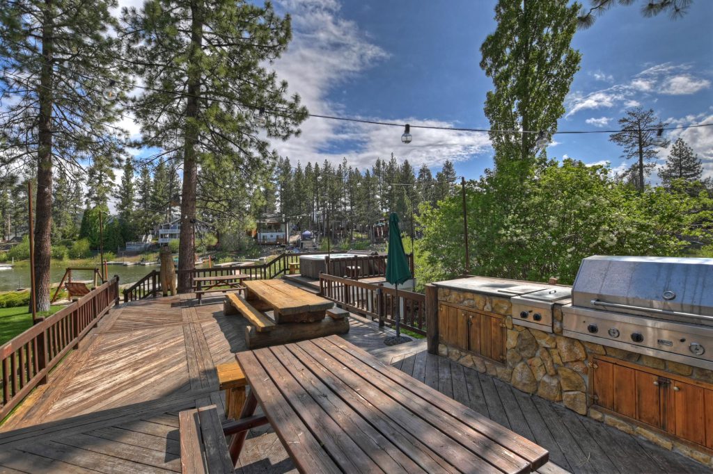 An outdoor deck with picnic tables and a built-in barbecue grill overlooking the lake in Big Bear