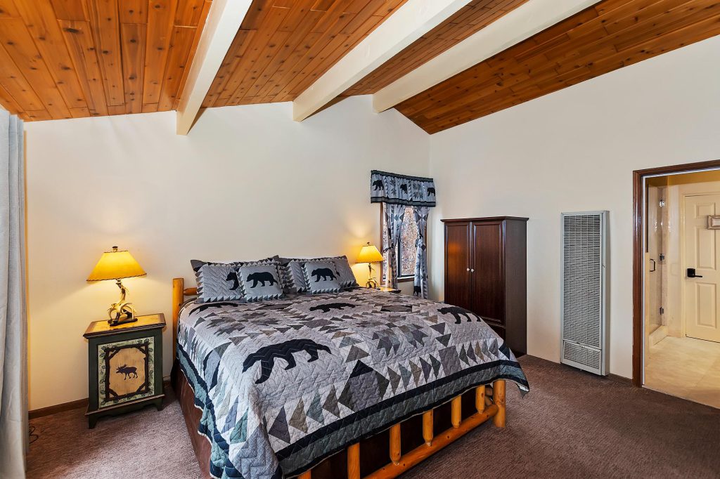 A cozy bedroom with rustic wooden ceiling and bear-themed decor at Big Bear.