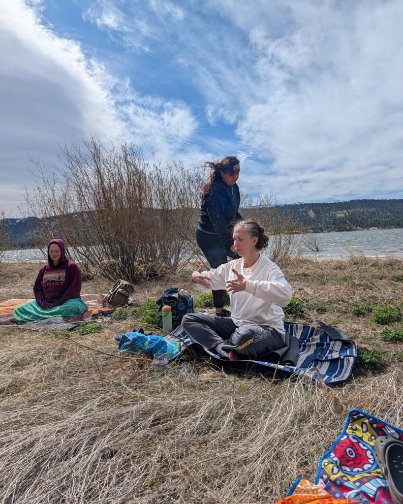 Women participating in a peaceful outdoor gathering near the lake during the Summer Solstice event.