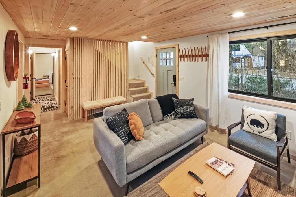 Modern mountain cabin living room with gray sofa, wood slat accent wall, and large picture window