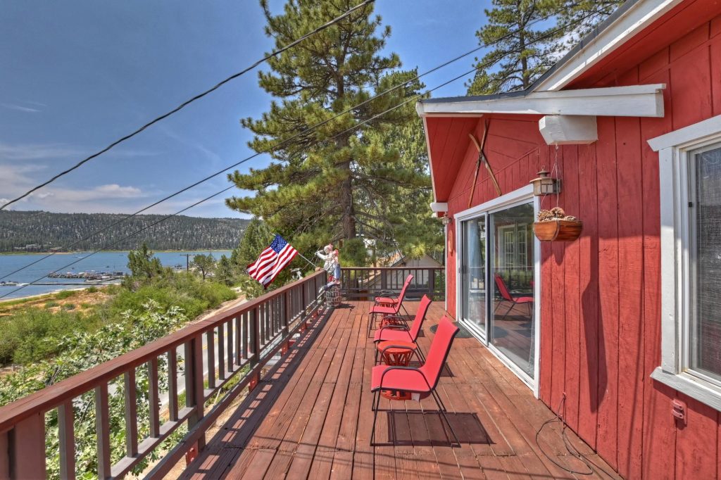 Lakefront deck at Tippie Canoe cabin with red exterior, outdoor seating, and scenic Big Bear Lake views.