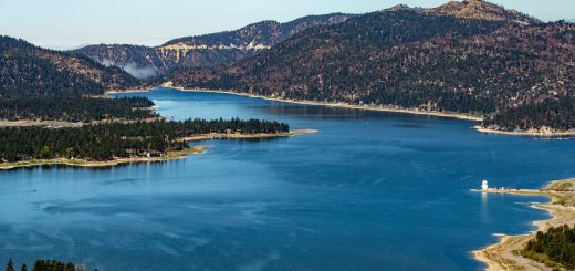 Panoramic view of Big Bear Lake surrounded by lush green forests and mountains under a clear blue sky