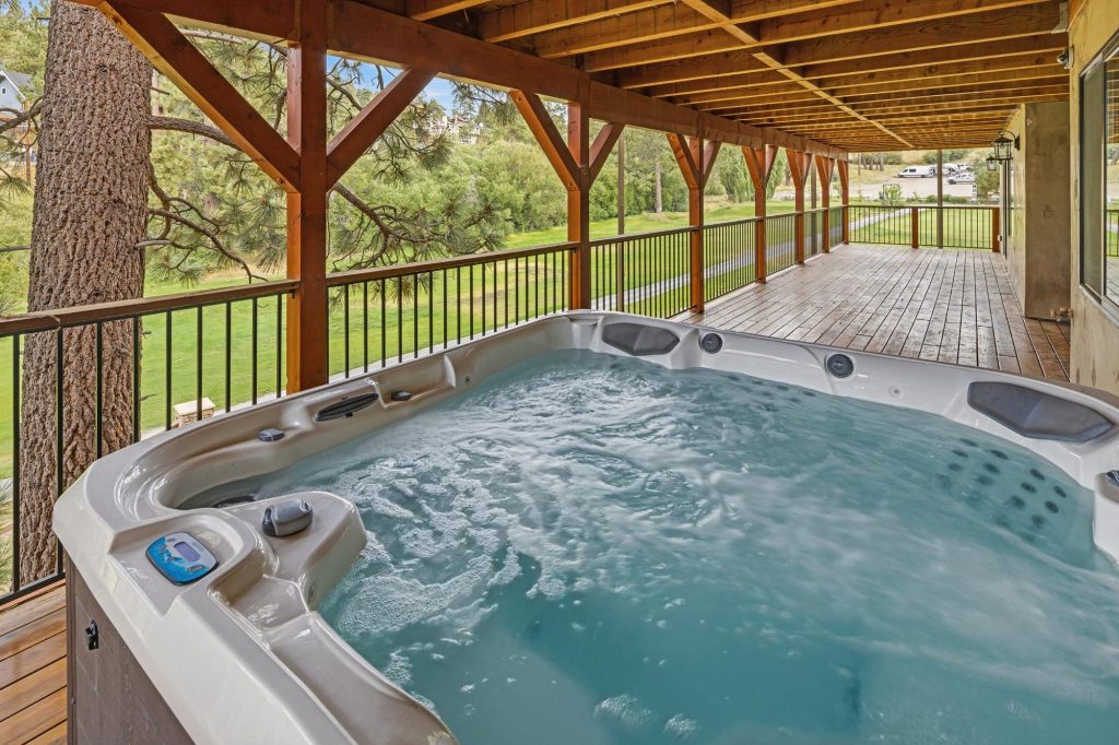 Outdoor jacuzzi at Villa Felicita featuring a spacious wooden deck, covered patio area, and peaceful mountain surroundings