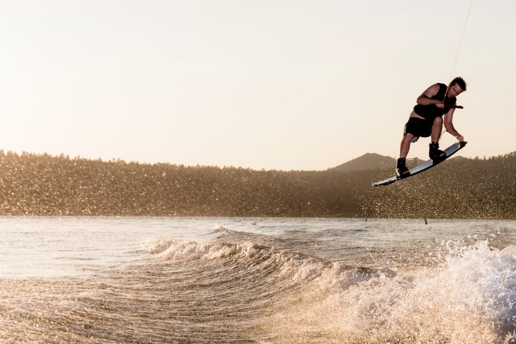 Wakeboarder performing jump tricks on Big Bear Lake during sunset