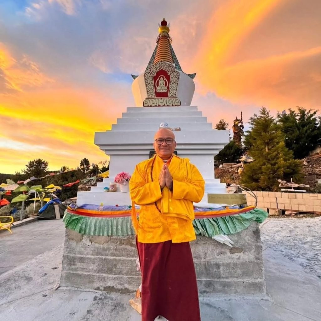 Monk standing in front of a Buddhist monument during sunset at a wellness gathering in Big Bear