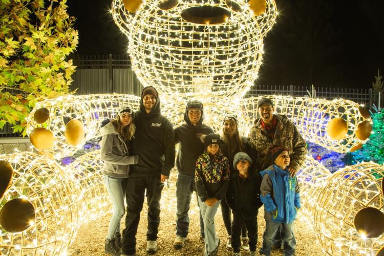 Family enjoying a holiday light display at Wild Lights with a glowing bear sculpture
