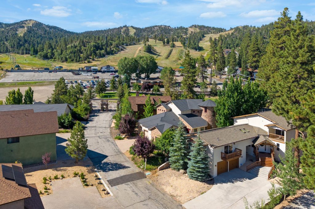 Aerial view of the Wolf Den neighborhood with homes, pine trees, and Bear Mountain ski area in the background