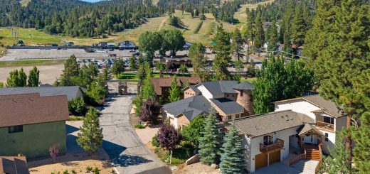 Aerial view of the Wolf Den neighborhood with homes, pine trees, and Bear Mountain ski area in the background