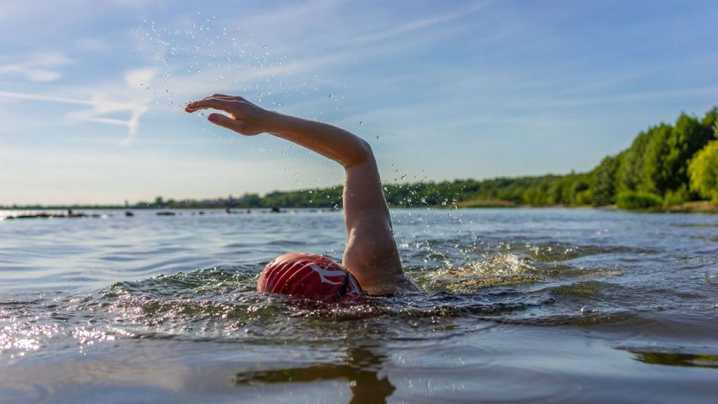 Swimmer enjoying an open water swim on a scenic lake surrounded by nature.