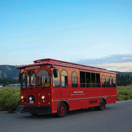 Red Big Bear trolley bus providing local transportation with mountain scenery in the background