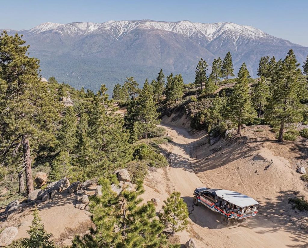 A jeep drives along a dirt road with mountains in the background near Big Bear, showcasing a scenic outdoor adventure.