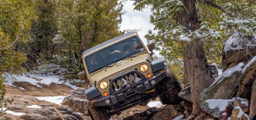 A jeep navigating a snowy, rocky trail in Big Bear, surrounded by winter scenery.