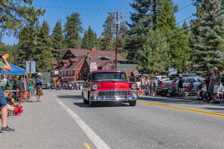 Classic vintage car driving through a community parade in Big Bear Lake with spectators lining the street.