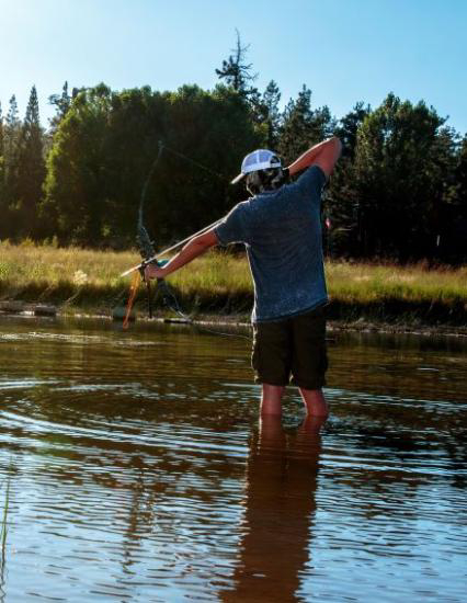 Person fly fishing in Big Bear Lake surrounded by scenic mountain landscape