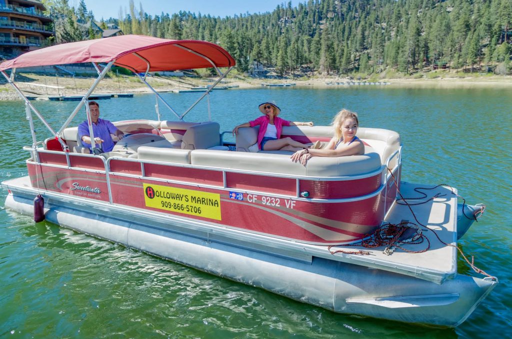 Three people on a pontoon boat from Holloway's Marina on Big Bear Lake.