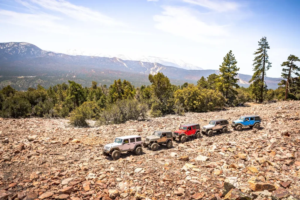 Four off-road jeeps parked on a rocky hillside in Big Bear, showcasing the rugged landscape and outdoor adventure.
