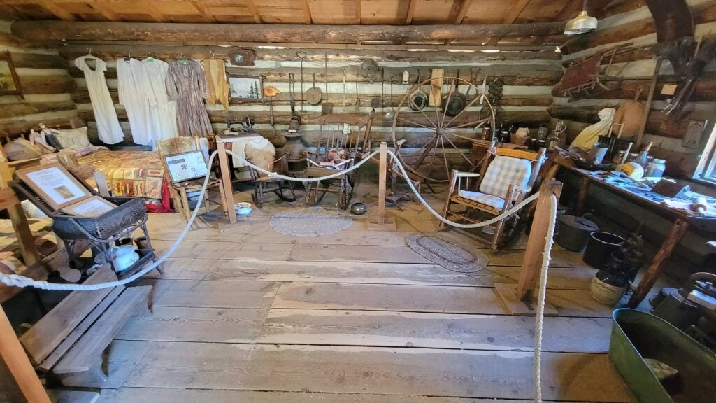 Interior of a pioneer-era cabin exhibit at the Big Bear Valley Historical Museum featuring antique furnishings and artifacts.
