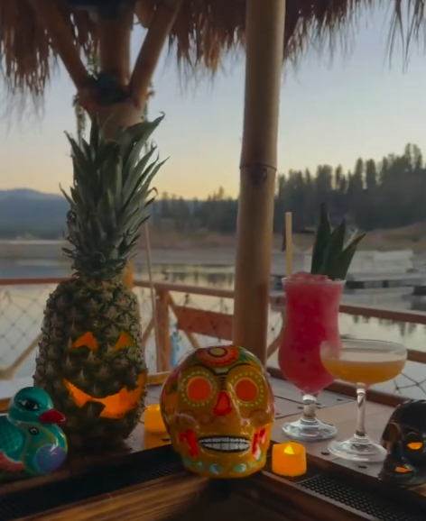 Halloween-themed tiki bar setup with tropical drinks, pineapple decor, and spooky skull decorations